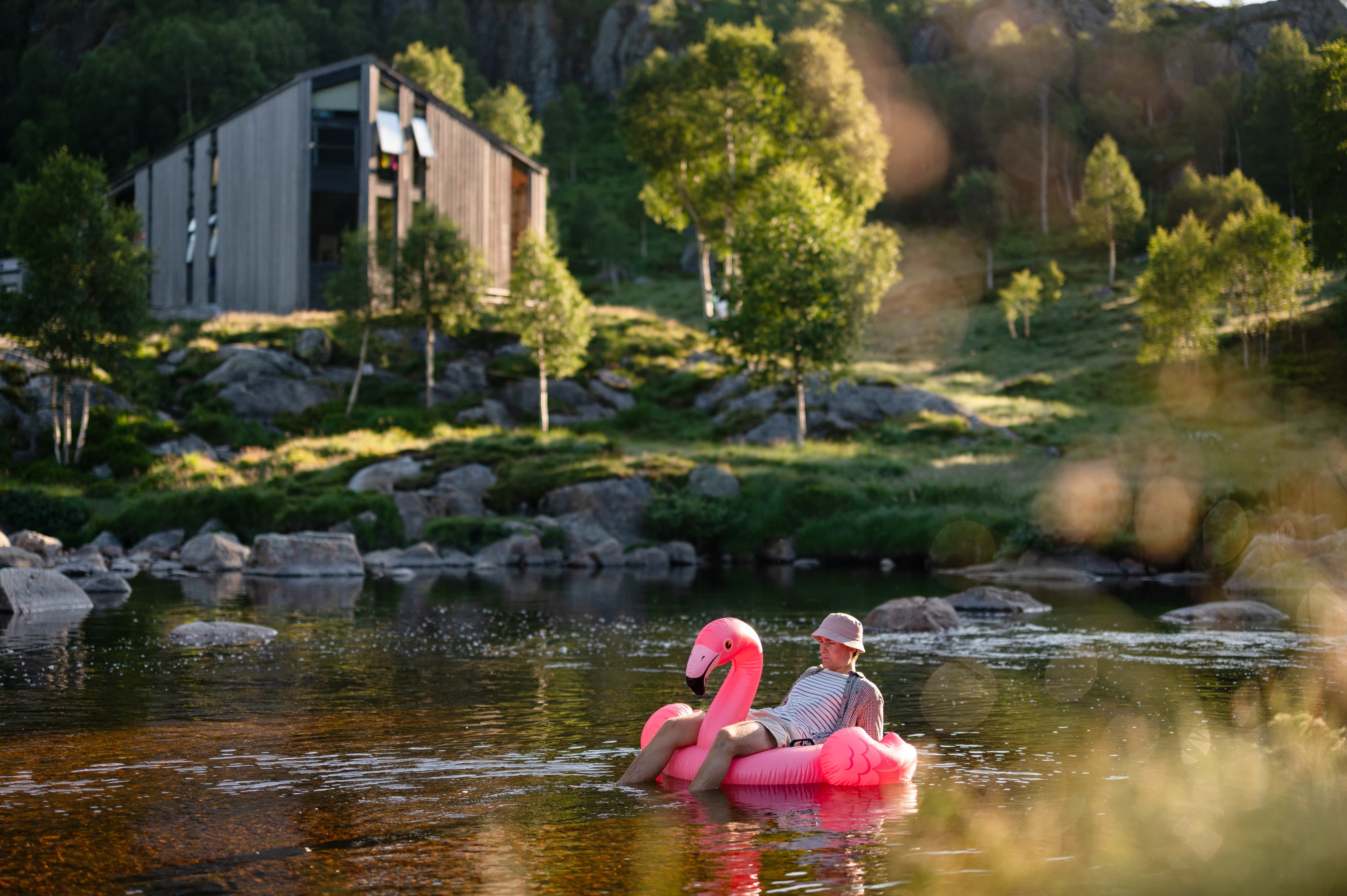 Stemningsbilde fra badeplass med utsikt mot moderne trehus i landskapet